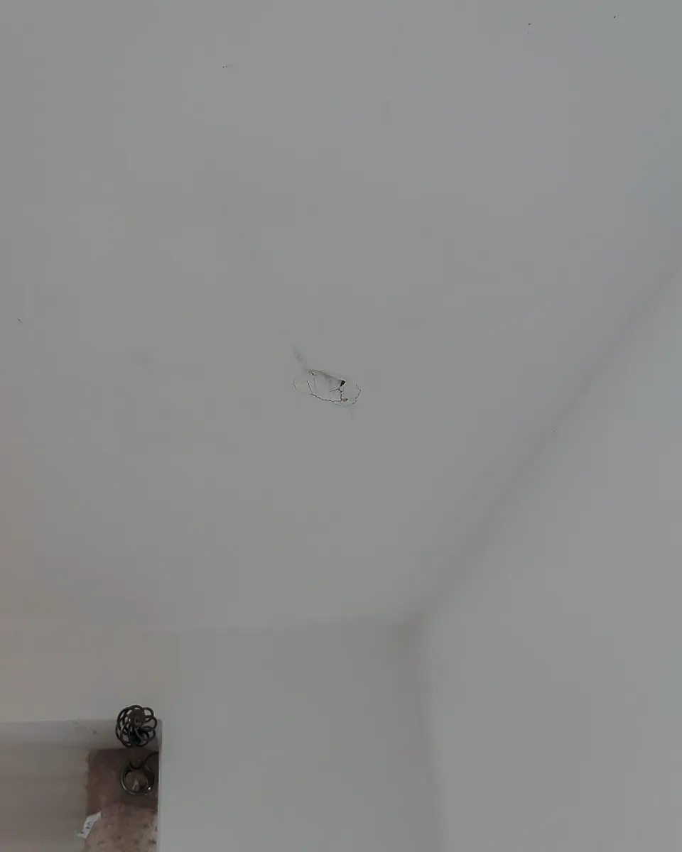 Agujero en el cielo raso de gypsum antes de la reparación