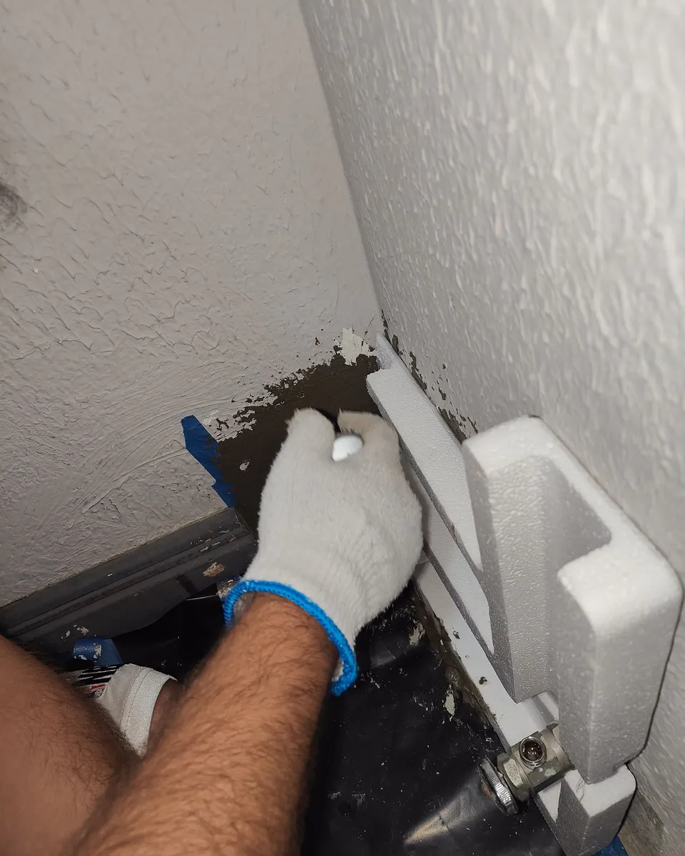 Técnico resanando la pared junto a la tubería
